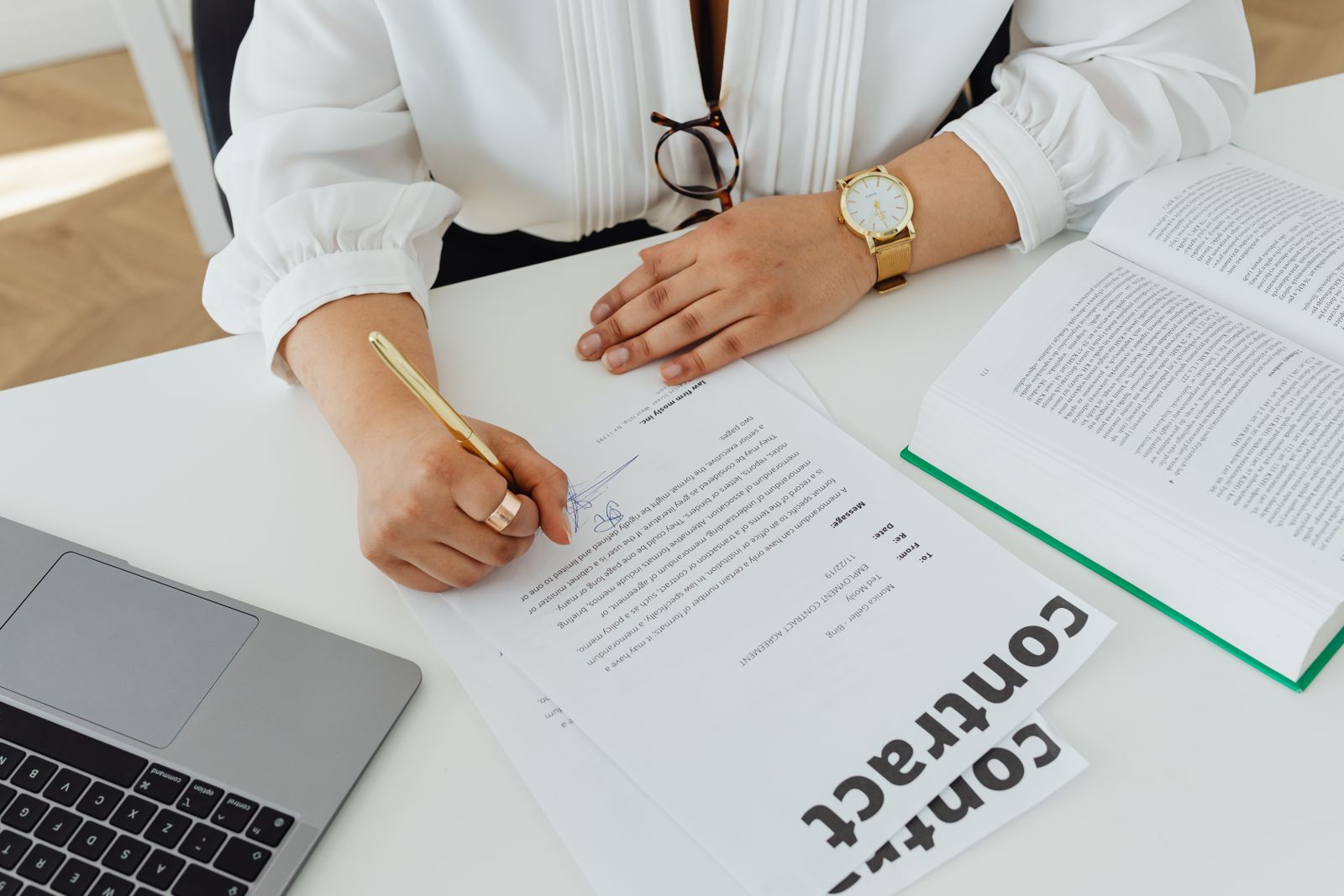 Person signing a contract document at a desk
